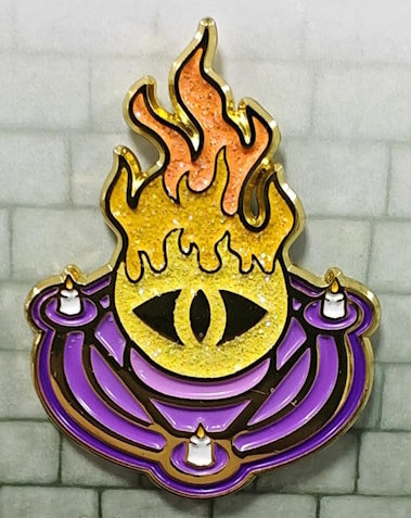 Soft enamel pin with a Warlock's purple summoning circle with 3 white candles, from which multi-colored flames rise with an all-seeing eye staring from the base of the fireball.