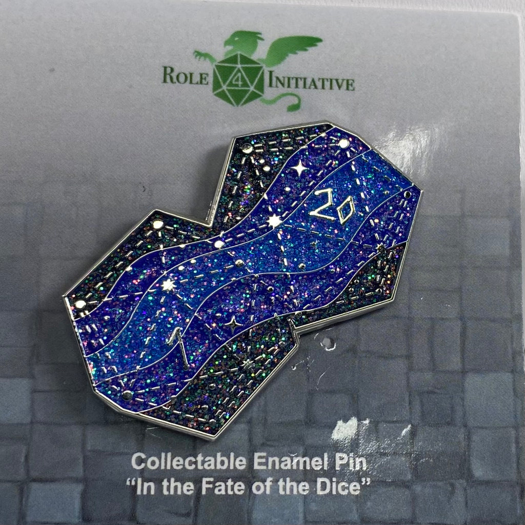 Soft enamel pin named "In the Fate of the Dice", showing 2 attached d20s as the night sky, with 3 shades of blue waves moving across the dice, and silver dotted lines depicting constellations. There are 3 shades of holographic glitter across the waves of blue.