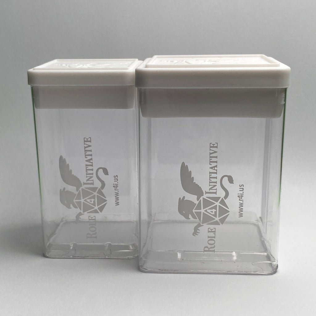 Image shows an example of 1 small and 1 large clear plastic TTRPG dice boxes with white lids. The clear  container has the Role 4 Initiative griffin logo in white on 1 side, and the white lid has a raised griffin with d20 logo  in the center, with a raised lip near the edge for easy stacking of multiple boxes.